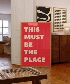 this must be the place sign in front of a red poster on a wooden table