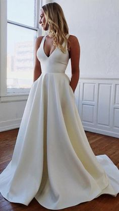 a woman in a white dress standing on a wooden floor with her back to the camera