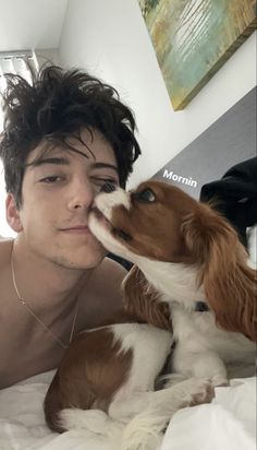 a young man laying in bed with his dog