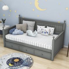 a child's room with a bed, dresser and night sky wall decal