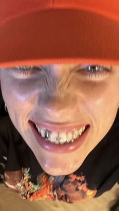 a young boy wearing an orange hat and smiling at the camera with his teeth missing