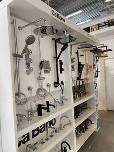 a white shelf filled with lots of different types of shower heads and faucets