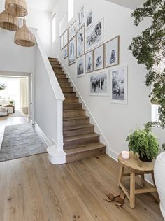 a woman is walking up the stairs in her home with pictures on the wall behind her