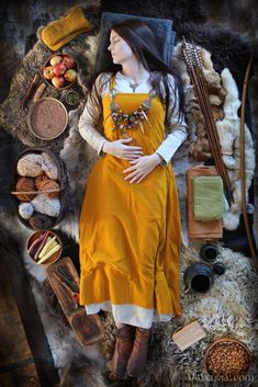 a woman in an orange dress laying on top of a pile of fur and other items