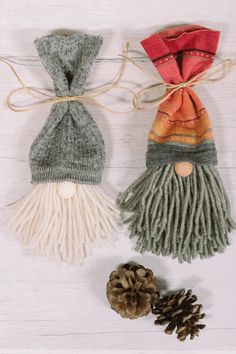 two knitted gnome ornaments with pine cones on the side