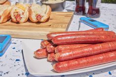 several hot dogs on a plate next to a cutting board