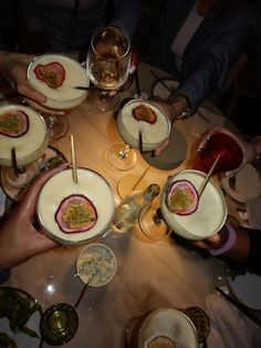 a group of people sitting around a table with food and drinks in bowls on it