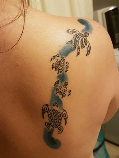 the back of a woman's shoulder with blue watercolor tattoos on her left side