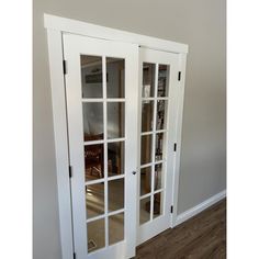 an empty room with white doors and wood floors