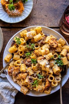 pasta with meat and parmesan cheese on a plate next to a glass of wine