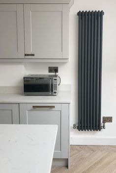 a white kitchen with an oven, microwave and toaster on the counter next to the radiator