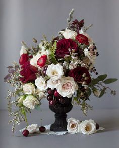 a black vase filled with red and white flowers on top of a gray tablecloth