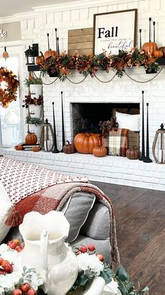 a living room decorated for fall with pumpkins and greenery on the mantel