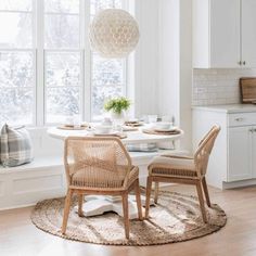 a dining room table with two chairs and a round rug on the floor in front of it