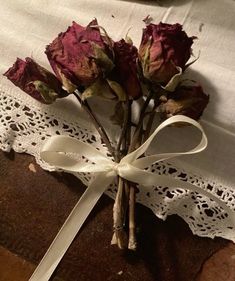 a bouquet of roses is tied to a piece of fabric on a tablecloth with lace