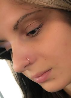 a close up of a woman with a nose piercing on her nose and one eye open