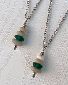 Cairns have long been used to mark trails and paths so that we don’t lose our way in the wilderness. Take a little bit of the trail with you wherever you go with this dainty cairn necklace. Three hand drilled pebbles and a heishi glass bead are hung on small stainless steel chain. Comfortable and easy to wear. Stainless steel chain and findings won’t tarnish, and won’t irritate sensitive skin. -Stainless steel findings and chain -Hand drilled natural beach pebbles and a green glass heishi bead - Beach Rock Jewelry, Cairn Necklace, Beach Pebbles, Green Flats, Beach Rocks, Rock Jewelry, Heishi Beads, The Wilderness, Cairns