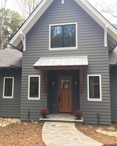 a gray house with white trim on the front door and two windows in the side