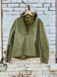 For your consideration is a great vintage WWII era 1940's military jacket. Made for foul weather for the USN, It pulls over the head and has a laced chest front and drawstring bottom. Hooded. There are ventilation grommets at the underarms. It feels to be a coated water resistant cotton. Marked a size M 44" chest ptp 21" shoulder seams 26.5" sleeve length 25" length Condition is govern good. There are a few marks on the fabric that give it a nice patina. Drawstrings are all present.  Please see pics and ask any questions prior to purchasing as all sales are final. Price includes shipping in the USA! Thanks for looking! Japanese 80s, Deck Jacket, Pilot Jacket, Concept Clothing, Vintage Japanese, Design Inspo, Military Jacket, Mens Jackets, Water Resistant