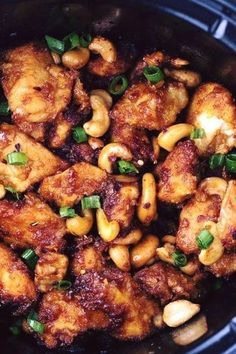 chicken and cashews in a crock pot with green onions on the side