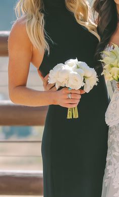 two beautiful women in dresses holding bouquets of flowers