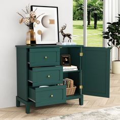 a green cabinet with three drawers and some pictures on it's sideboard next to a window