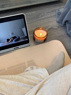 a laptop computer sitting on top of a wooden table next to a person laying in bed