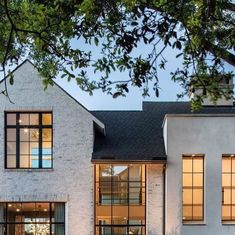 a white house with lots of windows and lights on it's front door is lit up at night