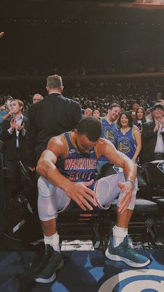 a basketball player kneels down in front of the crowd