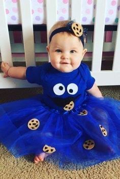 a baby wearing a blue dress with cookie cookies on it's chest and smiling at the camera