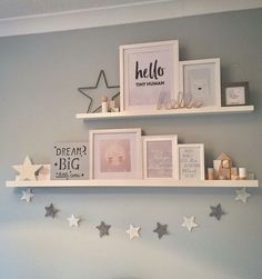 two white shelves with pictures on them and stars hanging from the wall in front of them