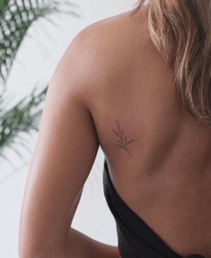 the back of a woman's shoulder with a small flower tattoo on her left side