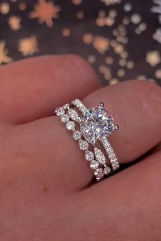 a woman's hand with a diamond ring on top of her finger and the other hand holding it