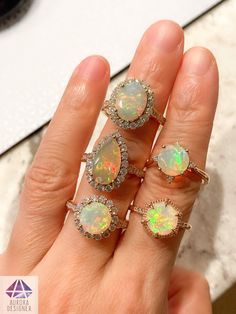 a woman's hand with five opal and diamond rings