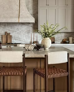 two chairs sitting at a kitchen island with marble counter tops and cabinets in the background