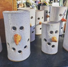 several ceramic vases with holes and shells painted on them