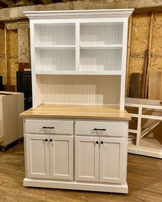 a white hutch with two doors and cupboards in the middle of a room