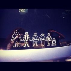 a group of paper cut out figures sitting on top of a car's hood