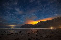 the night sky with stars and clouds over mountains at low tide beach in new zealand