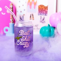 a purple glass with a straw in it sitting on a table next to some balloons