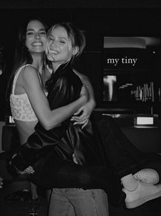 two women hugging each other in front of a black and white photo with the words, my tiny