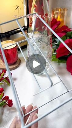 a person holding a wine glass in front of a vase filled with flowers and candles