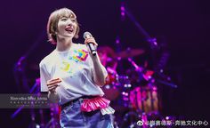 a woman standing on stage holding a microphone