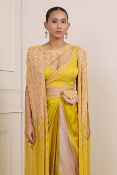 Yellow cape with sequin, bead, cutdana, pearl embroidery in geometric pattern. Paired with backless angrakha padded choli, dhoti skirt, belt and bag. - Aza Fashions Cape Sleeve Blouse With Dupatta For Diwali, Navratri Dupatta With Cutdana And Cape Sleeves, Traditional Sharara With Gota Work And Cape Sleeves, Traditional Wear With Zari Work And Cape Sleeves, Pre-draped Saree With Cape Sleeves And Pallu, Bollywood Style Choli With Cape Sleeves And Cutdana, Fitted Anarkali Traditional Wear With Cape Sleeves, Anarkali Traditional Wear With Cape Sleeves, Fitted Anarkali With Cape Sleeves