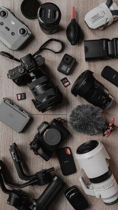 many different types of cameras and accessories on a table with a microphone in the middle