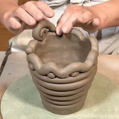 a person is making a vase out of clay