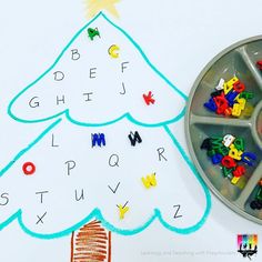 a child's christmas tree craft with letters and numbers on the tray next to it