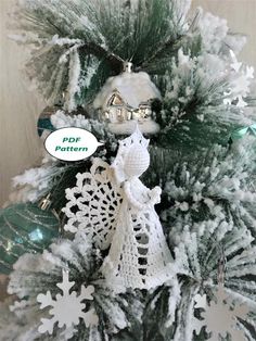 a crocheted angel ornament sitting on top of a christmas tree