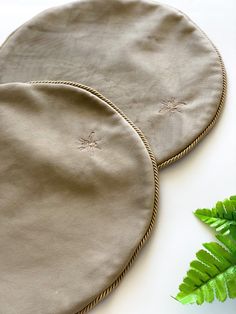 two round placemats sitting on top of a table next to a green plant