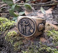 a ring with an image of two people holding hands on top of a moss covered rock